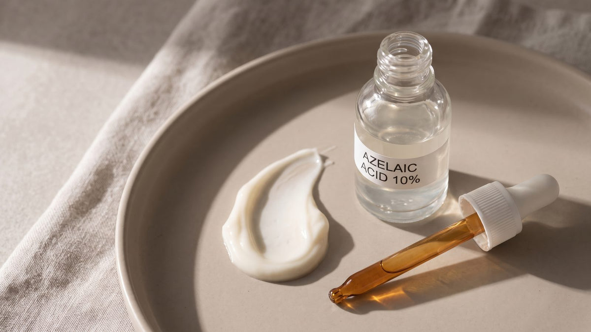 A bottle of 10% azelaic acid serum with a dropper and a swirl of cream on a stone plate